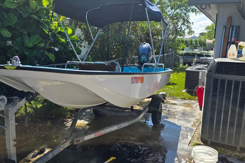 Slide: The Image of 1973 Boston Whaler 13 Sport boat on trailer, parked outdoors with canopy. - 1