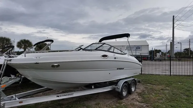 Slide: The Image of A white 2027 Stingray 22DC boat is on a trailer in an outdoor setting. - 1