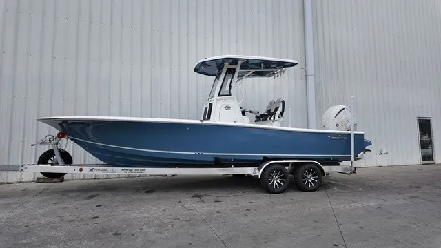 The Image of A blue 2027 Tidewater 2500 Carolina Bay boat on a trailer in front of a building. - 0