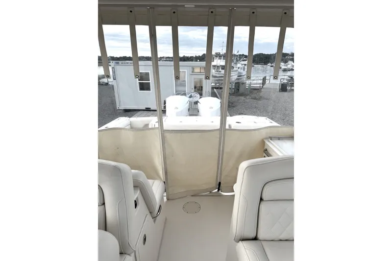 Slide: The Image of 2020 Grady-White Freedom 325 boat interior with white seating and marina view. - 13