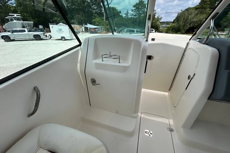 Slide: The Image of Interior view of a 2012 Pursuit DC 265 Dual Console boat, showcasing seating and storage. - 15