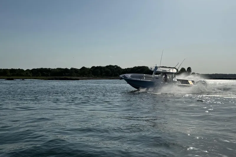 Slide: The Image of 2020 Southport 33 FE boat cruising on a sunny day near a forested shoreline. - 17