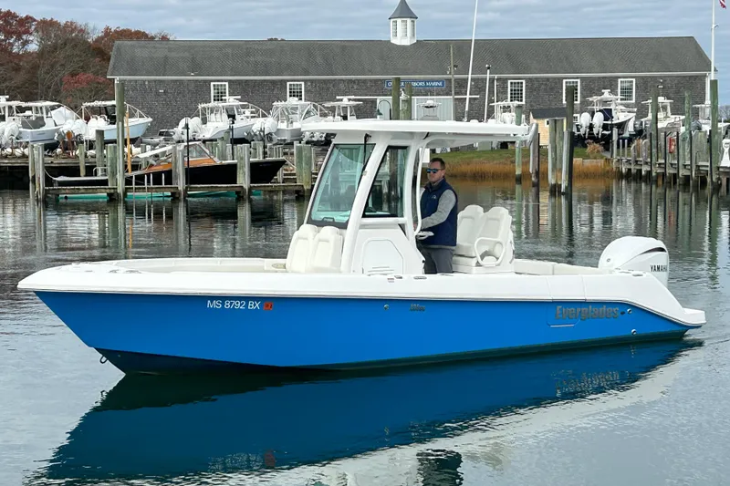 The Image of 2023 Everglades 235 Center Console boat docked at a marina with a person onboard. - 1