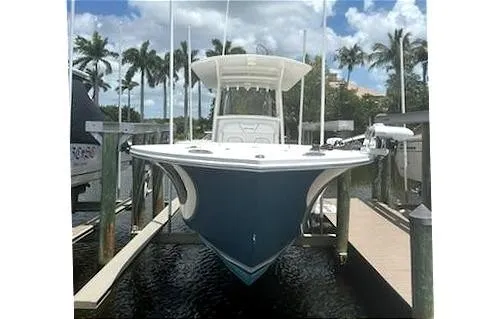 Slide: The Image of 2016 Regulator 28 Forward Seating boat docked, surrounded by palm trees and clear skies. - 7