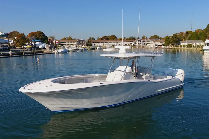 Slide: The Image of 2023 Mag Bay 33 CC boat on calm water, clear sky, marina background. - 10