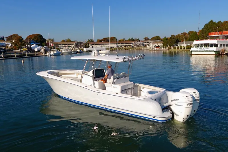 Slide: The Image of 2023 Mag Bay 33 CC boat on calm water, featuring twin Mercury 400 engines. - 8