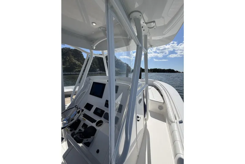 Slide: The Image of 2015 Regulator 25 boat cockpit with steering wheel and control panel on a sunny day. - 27