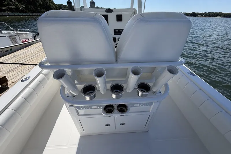 Slide: The Image of 2015 Regulator 25 boat interior with rod holders and seating, docked by the water. - 33