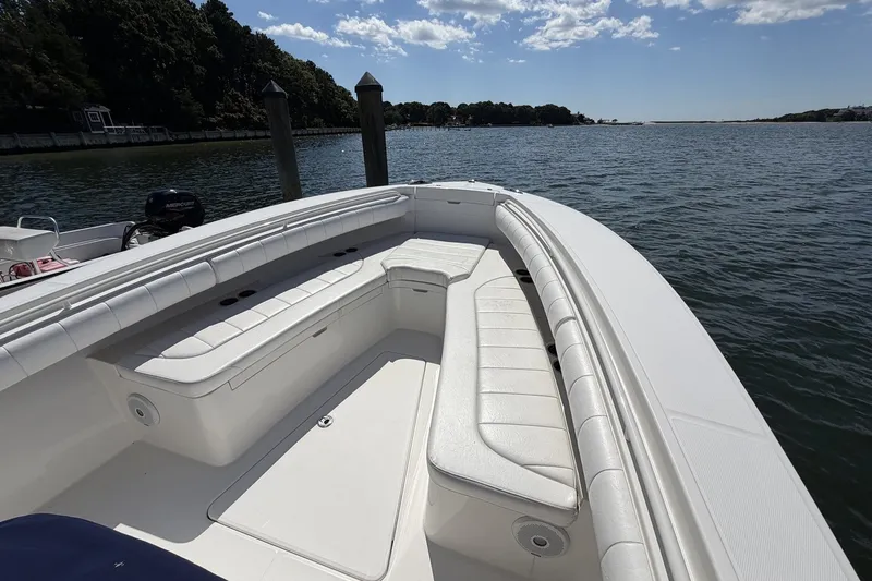 Slide: The Image of 2015 Regulator 25 boat with white seating, docked on a calm lake. - 19