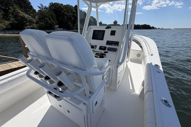 Slide: The Image of 2015 Regulator 25 boat interior with helm, rod holders, and seating on a sunny day. - 28