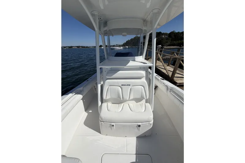 Slide: The Image of 2015 Regulator 25 boat with white seating, docked by a wooden pier. - 25