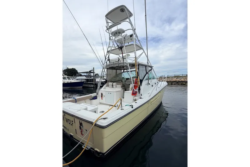 Slide: The Image of 2003 Rampage 38 Express boat docked in a marina, featuring a tall tower and fishing equipment. - 4