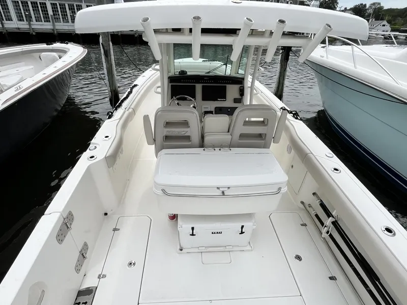 Slide: The Image of 2018 Boston Whaler 330 Outrage boat interior, featuring seating and helm, docked at marina. - 15