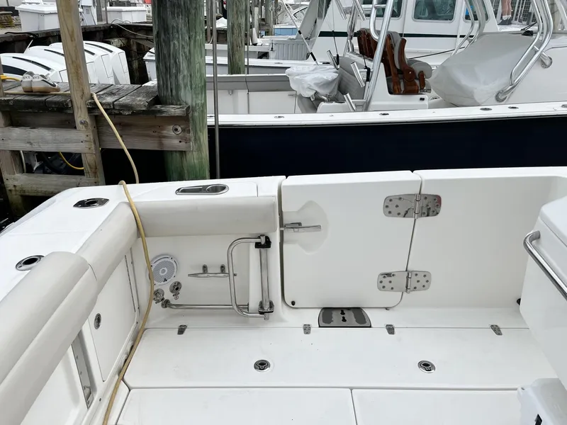 Slide: The Image of 2018 Boston Whaler 330 Outrage boat interior, featuring deck and seating area at dock. - 10