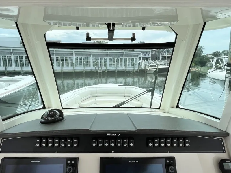 Slide: The Image of 2018 Boston Whaler 330 Outrage helm view with marina backdrop. - 23