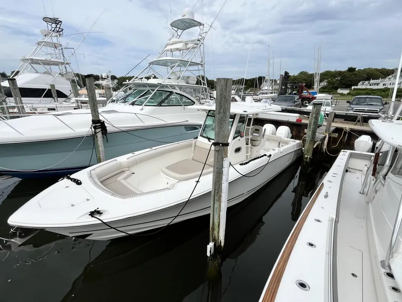 Slide: The Image of 2018 Boston Whaler 330 Outrage docked at a marina, surrounded by other boats. - 4