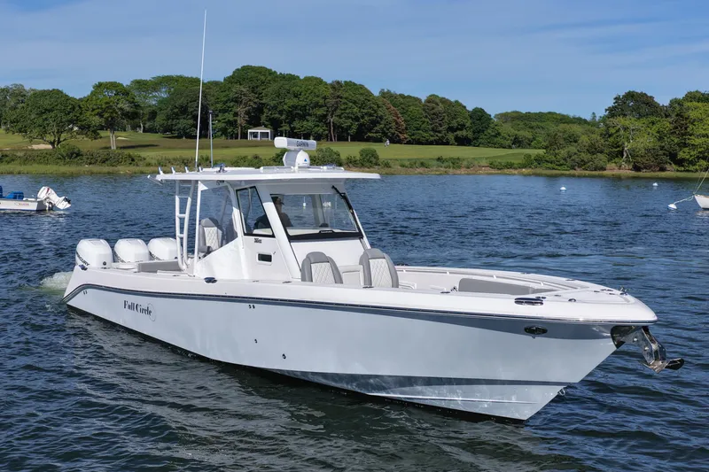 Slide: The Image of 2022 Everglades 365 Center Console boat cruising on a scenic lake with lush greenery. - 10