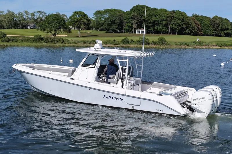 Slide: The Image of 2022 Everglades 365 Center Console boat cruising on a scenic lake with lush greenery. - 2