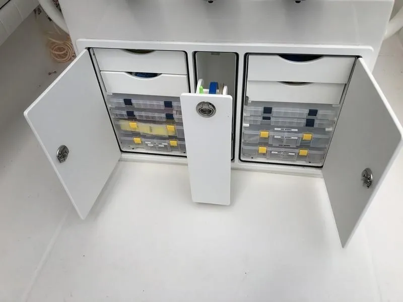Slide: The Image of 2018 Regulator 31 boat storage compartment with organized tackle boxes and open doors. - 17