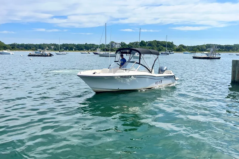 Slide: The Image of 2021 Grady-White Freedom 215 boat cruising on a scenic lake with other boats. - 7