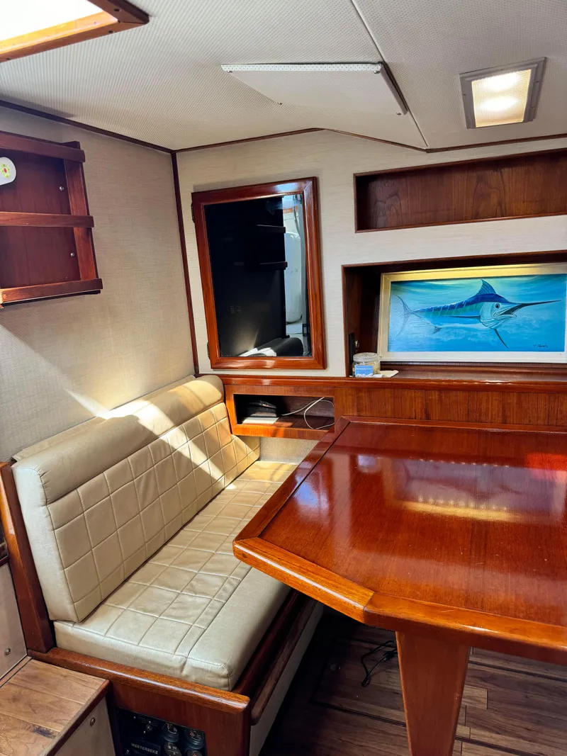 Slide: The Image of 1985 Viking Express boat interior with wooden table, cushioned seating, and nautical artwork. - 26