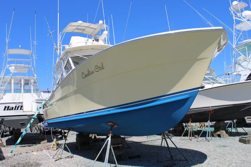 Slide: The Image of 1985 Viking Express boat on stands, beige hull, blue bottom, clear sky background. - 5