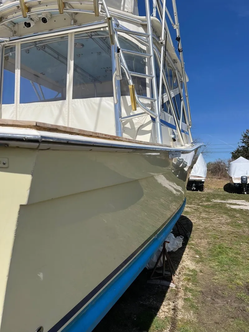 Slide: The Image of 1985 Viking Express boat with cream hull and blue bottom, docked on land under clear sky. - 6