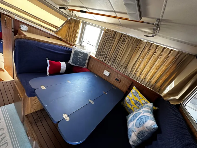 Slide: The Image of Interior of 1980 Bertram 33 Sport Fisherman with blue seating and foldable table. - 15
