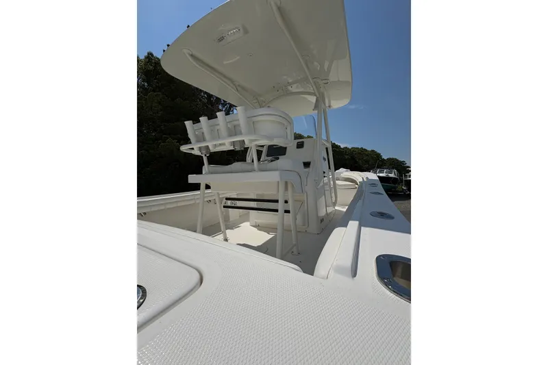 Slide: The Image of 2017 Regulator 23 Forward Seating boat with white interior and T-top under clear sky. - 21