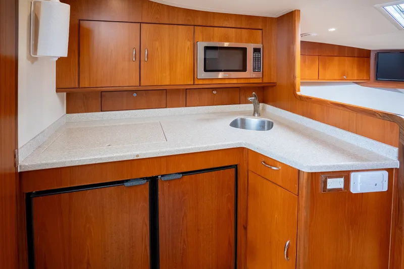 Slide: The Image of 2011 Cabo 36 Express yacht kitchen with wood cabinetry, sink, and microwave. - 42