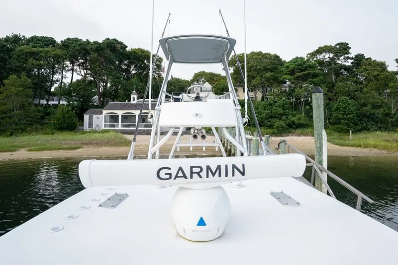 Slide: The Image of 2023 Invincible 39 Open Fisherman boat docked with Garmin equipment, surrounded by lush greenery. - 21