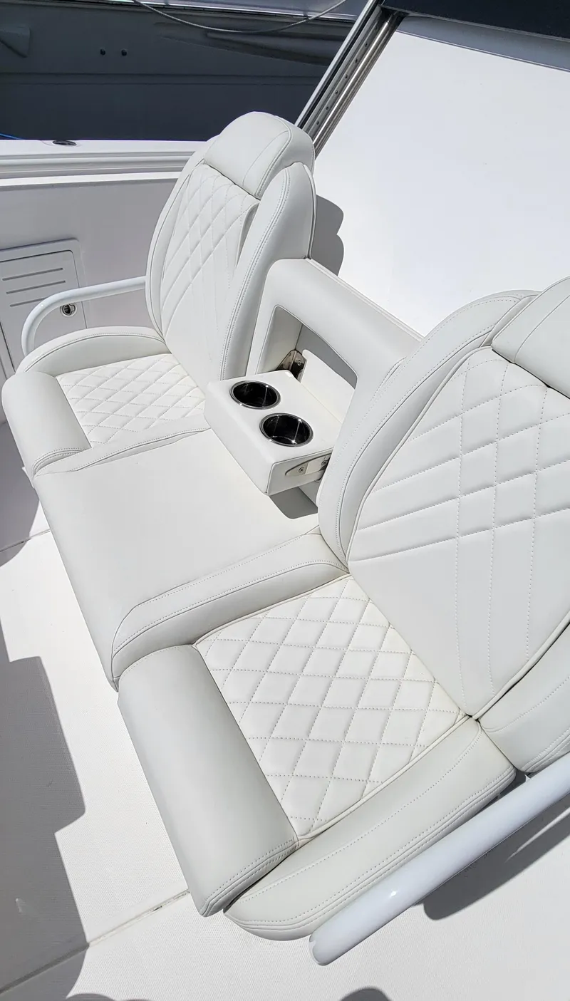 Slide: The Image of 2024 Everglades 365 Center Console boat seating with cup holders, featuring white quilted upholstery. - 17