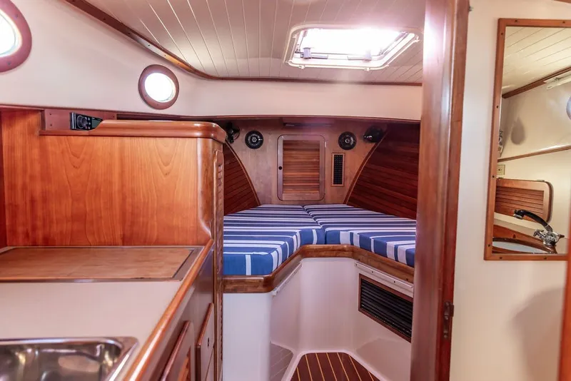 Slide: The Image of Interior of 1998 Hinckley Picnic Boat 36 Classic with wood finish and striped bedding. - 45