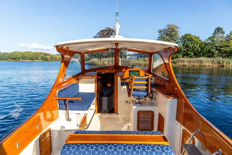 Slide: The Image of 1998 Hinckley Picnic Boat 36 Classic on serene lake, showcasing elegant wooden interior. - 20