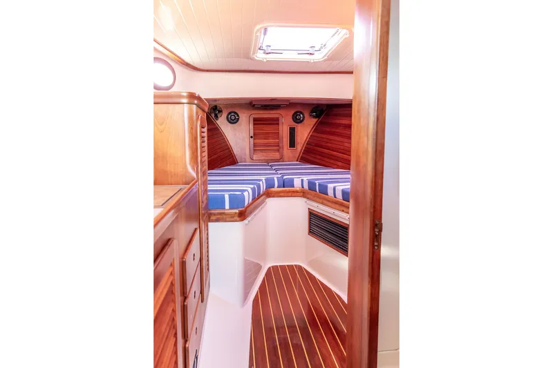 Slide: The Image of Interior of 1998 Hinckley Picnic Boat 36 Classic with striped bedding and wooden cabinetry. - 39