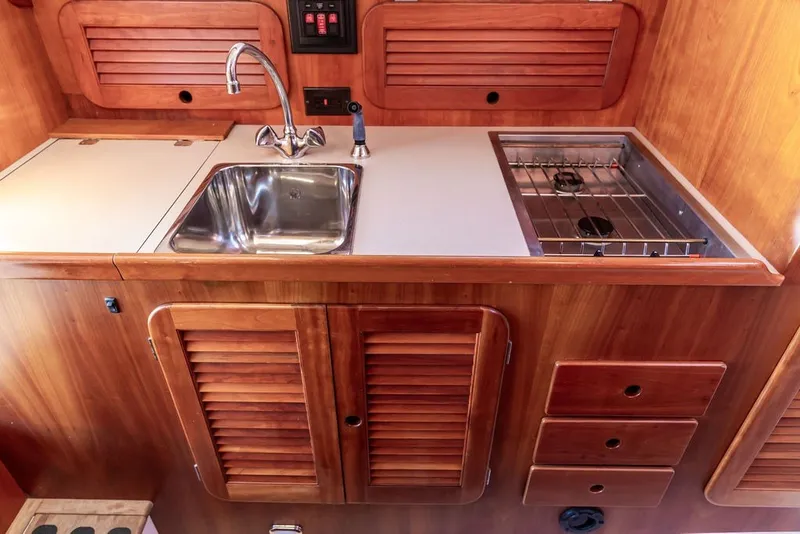 Slide: The Image of Hinckley Picnic Boat 36 Classic 1998 galley with sink, stove, and wooden cabinetry. - 40