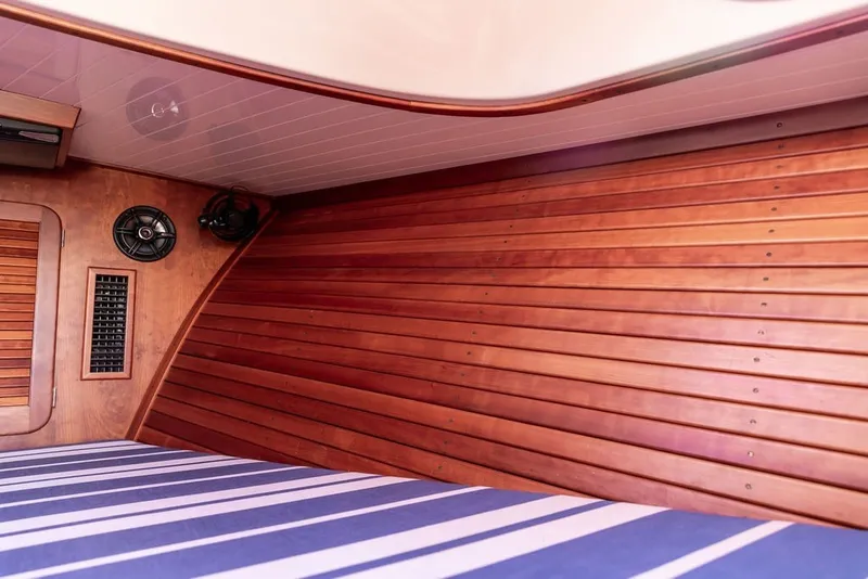 Slide: The Image of Interior of 1998 Hinckley Picnic Boat 36 Classic with wooden paneling and striped bedding. - 46
