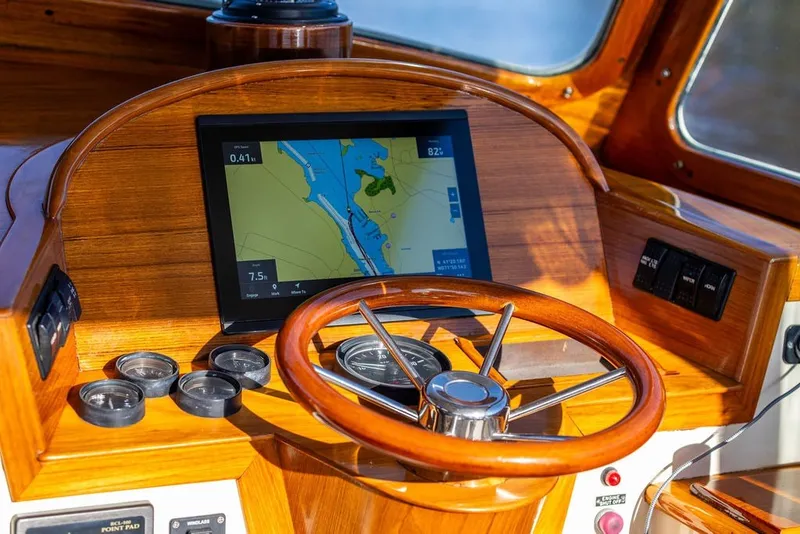 Slide: The Image of Helm of 1998 Hinckley Picnic Boat 36 Classic with navigation display and wooden steering wheel. - 30
