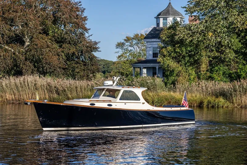 Slide: The Image of 1998 Hinckley Picnic Boat 36 Classic cruising on a serene river near a historic house. - 13