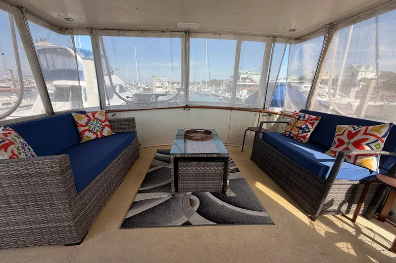 Slide: The Image of 1987 Viking 44 Motor Yacht interior with wicker seating, colorful cushions, and marina view. - 20