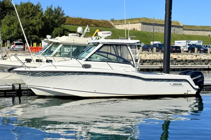 Slide: The Image of 2012 Boston Whaler 285 Conquest boat docked in a marina, reflecting on calm water. - 1