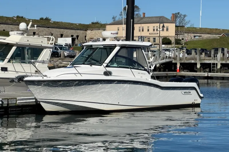 Slide: The Image of 2012 Boston Whaler 285 Conquest boat docked in a marina, reflecting on calm water. - 2