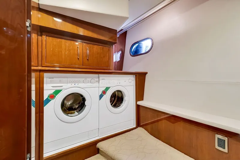 Slide: The Image of Laundry area in 2007 Marquis 65 yacht with washer and dryer, wooden cabinetry, and porthole window. - 42