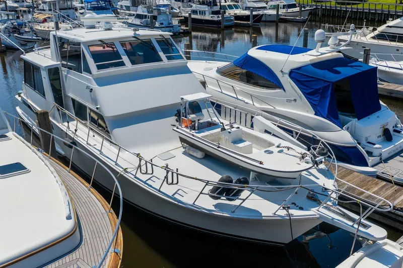 Slide: The Image of 1999 Viking 60 Cockpit Motor Yacht docked in a marina, surrounded by other boats. - 2