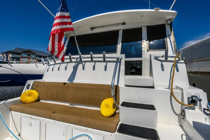 Slide: The Image of 1999 Viking 60 Cockpit Motor Yacht with American flag and cushioned seating. - 33