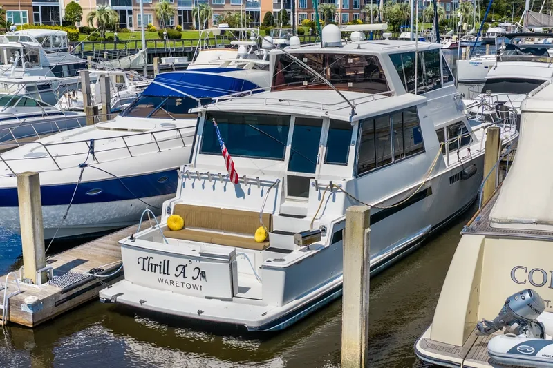 Slide: The Image of 1999 Viking 60 Cockpit Motor Yacht docked in marina, rear view with American flag. - 4