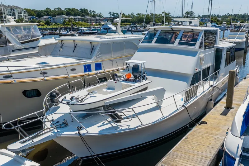 Slide: The Image of 1999 Viking 60 Cockpit Motor Yacht docked at a marina, showcasing sleek design and spacious deck. - 3