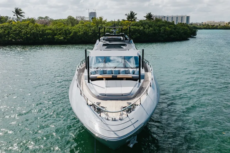 Slide: The Image of 2024 Mangusta 104 REV luxury yacht on serene water, surrounded by lush greenery. - 6
