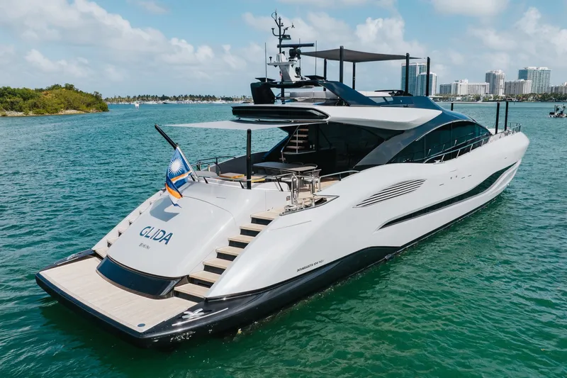 Slide: The Image of Luxurious 2024 Mangusta 104 REV yacht cruising in clear blue waters, showcasing sleek design. - 1