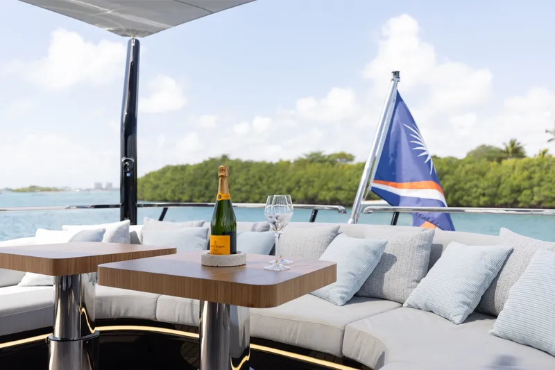 Slide: The Image of Luxurious 2024 Mangusta 104 REV yacht deck with champagne, cushions, and scenic water view. - 57
